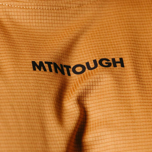 Close-up of a textured orange fabric with 'MTNOUGH' branding.