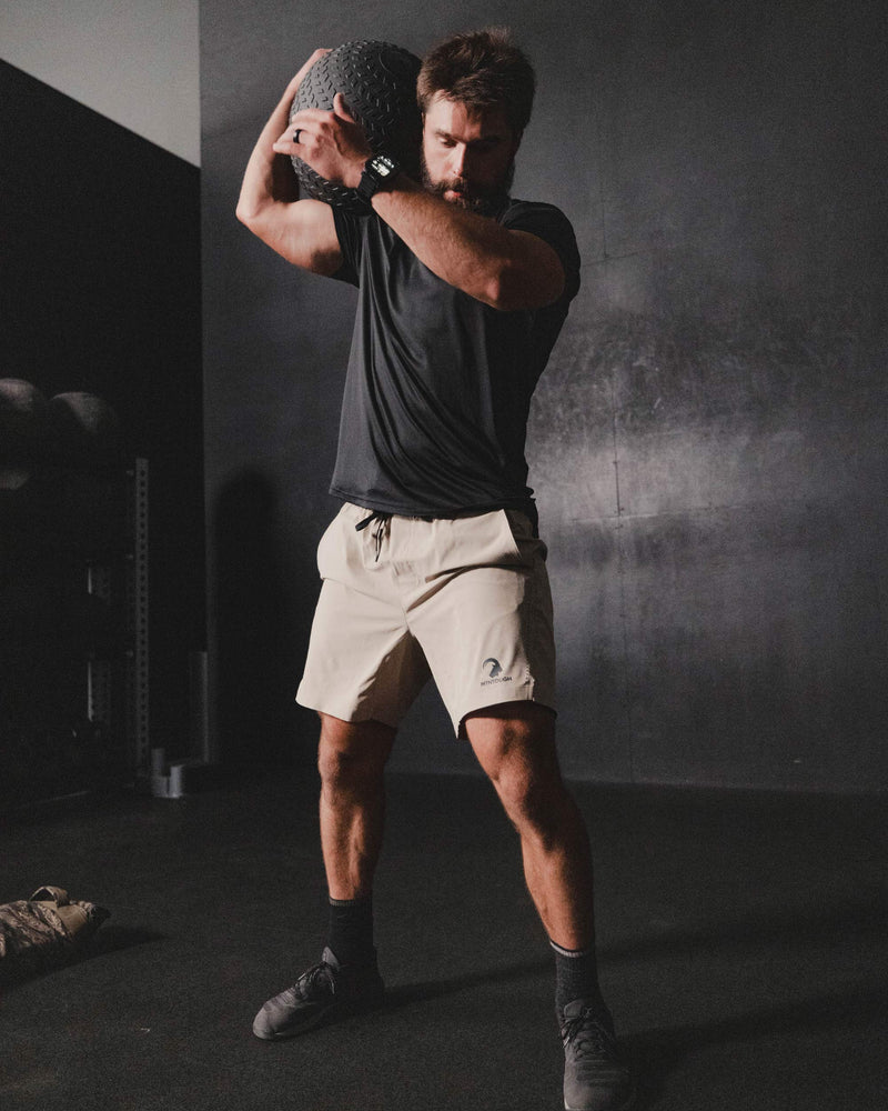 Man in athletic wear stretching in a dark room