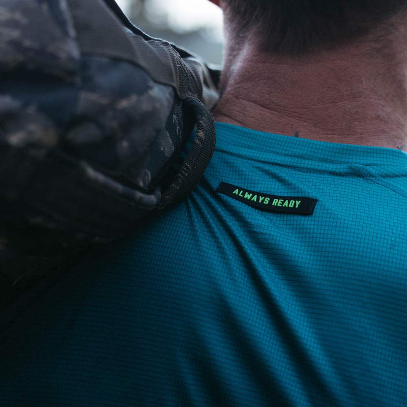 Person wearing a teal shirt with 'Always Ready' label, close-up on shoulder.